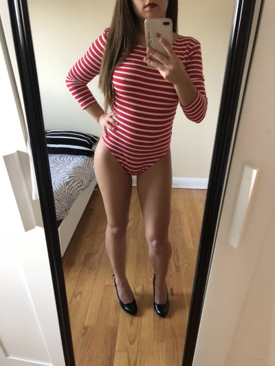 A beauty in a striped bodysuit twirled in front of the mirror and undressed